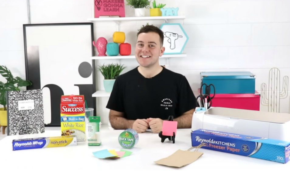 10 Things You Can Cut with Your Cricut - man pictured with composition notebook, aluminum foil, freezer paper, duct tape, cardboard boxes, sticky notes, and Cricut machine