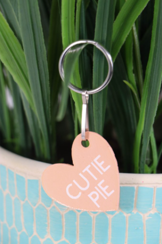 heart shaped keychain that looks like a conversation heart and says cutie pie on it