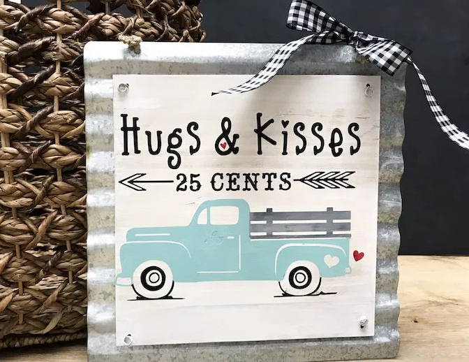Sign with vintage looking truck with an arrow underneath saying Hugs & Kisses 25 cents 