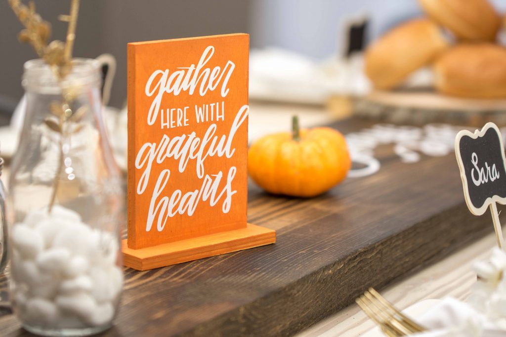 wooden sign as table decor saying gather here with grateful hearts
