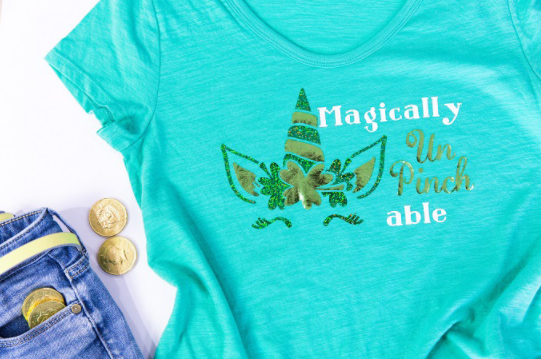 Green and gold unicorn head on tshirt with shamrocks. Text says Magically Unpinchable. 