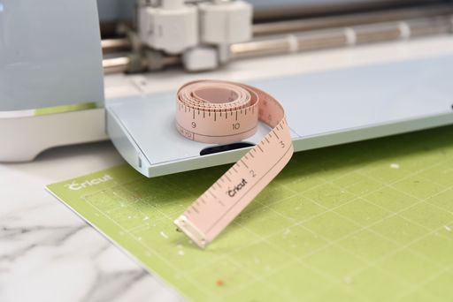 cricut measuring tape sitting on a cricut machine with a cricut standard grip cutting mat